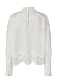 Blouse blanche à manches longues, ornée de détails en dentelle délicate sur le yoke et l'ourlet, avec des boutons décoratifs aux poignets et à l'arrière du col.