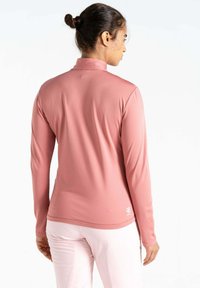 Langärmliges Sportoberteil aus weichem, pinkem Stoff. Merkmale einen hohen Kragen, ein aerodynamisches Design und ein kleines Logo auf dem unteren Rücken, mit einer glatten Textur.