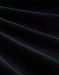 Tissu en velours côtelé noir avec des côtes prononcées, montrant une texture et une profondeur subtiles. La surface apparaît lisse et légèrement lustrée par endroits.