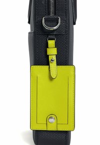 Bolso de cuero negro texturizado con una etiqueta de cuero amarilla. Incluye un acento de hardware plateado y un cierre superior con cremallera.