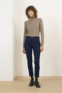Világosbarna garbós pulóver sötétkék, slim-fit farmernadrággal párosítva. Fekete fűzős cipő és sötét zokni egészíti ki a megjelenést.