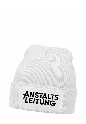 White knit beanie with a folded cuff, featuring a rectangular patch with "ANSTALTSLEITUNG" in bold black lettering. Textured, casual design.