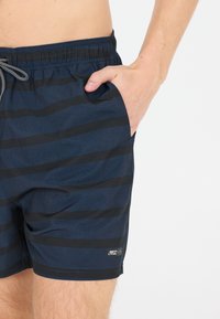 Shorts de bain bleu marine avec des rayures noires horizontales, taille élastique, cordon de serrage, poches latérales et un petit logo près de l'ourlet.