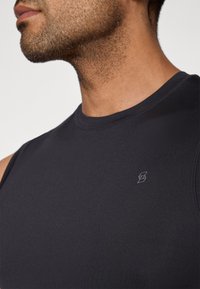 Fekete, ujjatlan sportpóló sima anyagból, kerek nyakkivágással és kis logóval a mellkason.