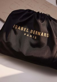Schwarze Satin-Zugtasche mit goldener Aufschrift "ISABEL BERNARD" und "PARIS". Glatte Textur mit einem gerafften Oben-Design.
