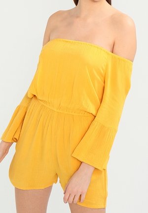 Romper amarillo sin hombros con mangas acampanadas, cintura ceñida y textura suave. Presenta un ajuste relajado y pantalones cortos hasta la rodilla.