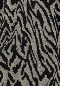 Tessuto nero e beige a fantasia con una texture pelosa, caratterizzato da un design astratto e frastagliato che ricorda i segni di animali.