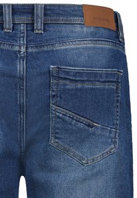 Dunkelblaue Jeans aus Denim mit einer hinteren Tasche mit gesteppten Nähten und einem braunen Lederlabel am Bund.