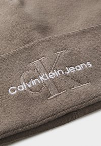 Smeđi pamučni beanie s izvezenim logotipom u tamnim i svijetlim nitima, s natpisom "Calvin Klein Jeans" ispod stiliziranog "CK."