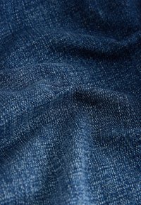 Țesătură din denim de culoare albastru închis cu o textură netedă, prezentând variații subtile în țesătură și o ușoară decolorare. Absența modelului sau a detaliilor notabile.