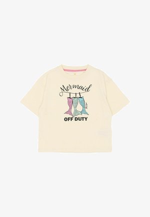 T-shirt crème à manches courtes avec un graphisme de trois queues de sirène colorées et le texte "Mermaid OFF DUTY" en noir.