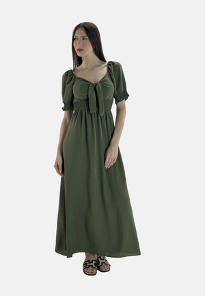 Maxi-jurk in olijfgroen, met pofmouwen, een strikdetail bij de halslijn en een geraffineerde taille. G gedragen met zwarte sandalen met patroon.