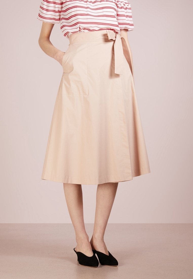 Falda A-line de color beige claro con bolsillos laterales, cintura ceñida y tela de algodón suave, que llega a la mitad de la pantorrilla. Diseño simple y limpio.