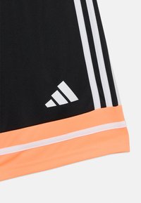 Calções de desporto pretos com riscas brancas e um detalhe pêssego na barra. Apresenta o logo da Adidas em branco no canto inferior esquerdo.