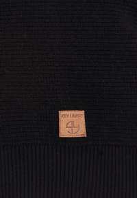 Schwarze Strickmütze aus strukturiertem Material mit geripptem Bündchen. Mit einem braunen Lederpatch mit eingeprägtem "KEY LARGO".