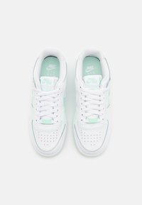 Baskets blanches Nike Air Force 1 avec des accents vert menthe, lacets noués, vues du dessus sur un fond blanc uni.