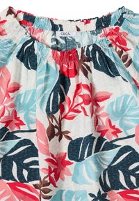 Blouse à encolure élastique avec imprimé feuilles et fleurs tropicales coloré en rouge, bleu, marron et blanc, portant l'étiquette "CECIL" à l'intérieur du col.