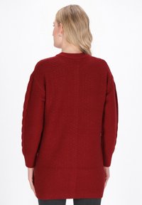 Czerwona, oversize sweter z teksturowanym wzorem dzianiny, z wplecionymi detalami na rękawach. Długa długość z okrągłym dekoltem.