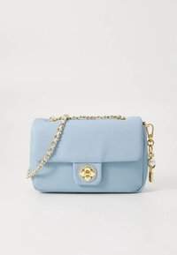 Světle modrá kožená kabelka se zlatým řetízkem, zapínáním na knoflík a ozdobným přívěskem s perlov ým prvkem.