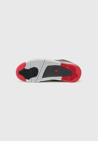 Schwarz-weißes Sport Schuhsohle mit einem roten Akzent, versehen mit strukturiertem Gummi für Grip und einem markanten Profil.