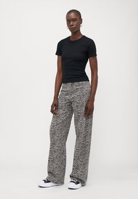 Black short-sleeve t-shirt paired with gray wide-leg pants featuring a zebra print. White sneakers complete the outfit.
