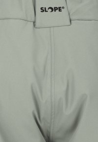 Harmaat housut, jotka on valmistettu sileästä kankaasta, ja joissa on vyötärönauhan logo "SLOPE" sekä näkyvät ompelutiedot.
