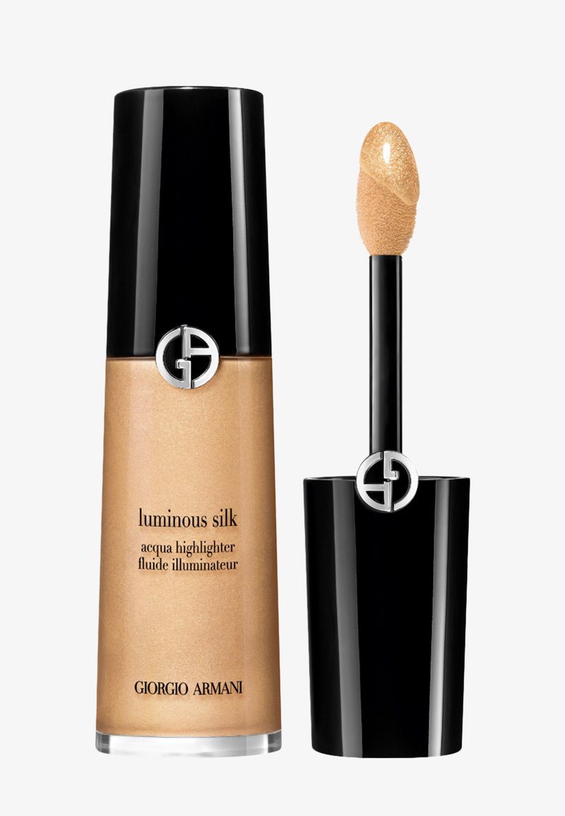L'illuminateur liquide Luminous Silk de Giorgio Armani dans un flacon en verre cylindrique transparent avec un capuchon noir ; il dispose d'un applicateur en forme de pied de doe.