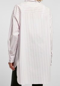 Chemise à manches longues avec rayures violet clair et blanches, col à boutons, coupe décontractée et ourlet droit. Manches avec poignets.