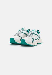 Baskets en mesh blanches avec des accents turquoise, dotées d'une semelle épaisse, d'une languette rembourrée et de détails texturés sur les côtés et les lacets.