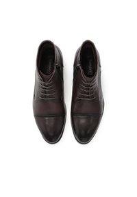 Rjavi usnjeni gležnjarji z gladkim zaključkom, okrašeni z vezalkami in zadrgo, zoženega oblika in z detajlom v kontrastni barvi na prstih.