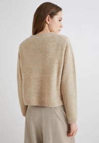 Maglione in lana beige con finitura testurizzata, design cropped e orlo a coste. Schiena senza cuciture con scollatura rotonda e maniche lunghe.