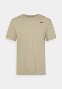 Camiseta de manga corta Nike en beis, fabricada con algodón suave, con un logo negro en el hombro izquierdo y un diseño clásico de cuello redondo.