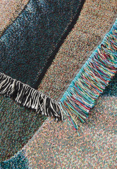 Textured woven blanket featuring a multicolored pattern, with frayed edges in black and vibrant hues of blue, red, and green.