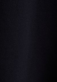 Ciemnoniebieska tkanina o teksturowanym, winnym wzorze. Materiał wygląda na gęsty i solidny, z delikatnym połyskiem odbijającym światło.