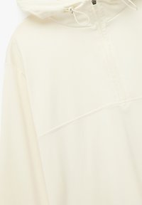 Lys beige pullover hoodie med halv lynlås foran, justerbar snoretræk i hætten og subtile syninger. Glat stofstruktur.