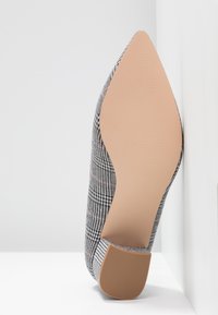 Escarpin à bout pointu en motif pied-de-poule noir et blanc, rehaussé de rose. Semelle lisse, hauteur de talon modérée et finition texturée.