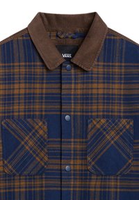 Rutig skjorta med en krage i brun kordflors, i blå och bruna nyanser, två framfickor och tryckknappar. Tillverkad av ett mjukt material.