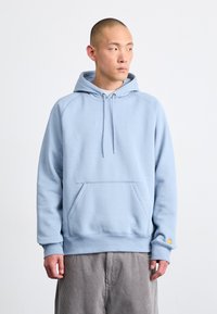 Hanorac bleu deschis cu buzunar marsupiu, glugă cu șnur și manșete ribbed. Dispune de mâneci raglan și un mic logo pe margine.