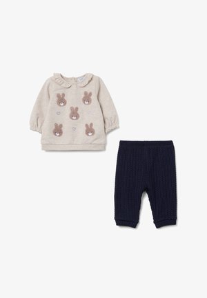 Sudadera beige con mangas abullonadas, con apliques texturizados de conejitos y corazones. Pantalones de punto acanalado azul marino con cintura elástica.