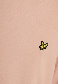 Μαλακό ροζ ύφασμα με ένα μικρό κεντητό κίτρινο π ουλί με μαύρο περίγραμμα στη δεξιά πλευρά, που δείχνει υφή πλεξίματος.