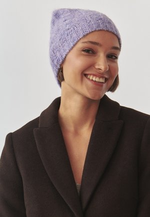 Berretto di maglia viola con una texture morbida e punta, indossato con un cappotto scuro. Presenta un design a coste e una vestibilità rilassata.