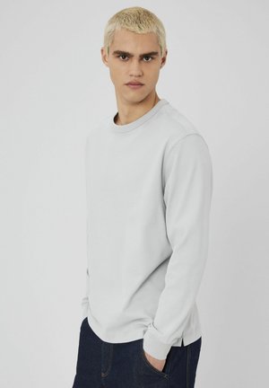 Sweatshirt à manches longues gris clair avec un col rond, fabriqué à partir de tissu doux. Dispose de poignets côtelés et d'une coupe décontractée pour un confort optimal.