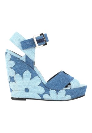 Sandale compensée avec brides en denim et boucle, présentant des motifs floraux bleu clair sur un talon plateforme en denim bleu foncé.