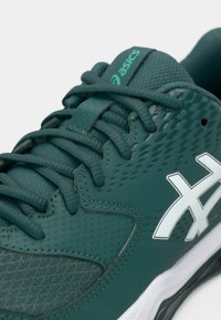 Πράσινο αθλητικό παπούτσι με υφασμάτινο επάνω μέρος, γλώσσα από δίχτυ, επίπεδα κορδόνια και λευκό λογότυπο. Λείο πέλμα με διακριτικές λεπτομέρειες και σχεδιασμό πρόσφυσης.