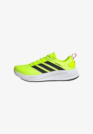 Neongele hardloopschoen met zwarte Adidas-strepen, witte zool met de opdruk "Dreamstrike" en de tekst "Supernova Ease 2" aan de zijkant.