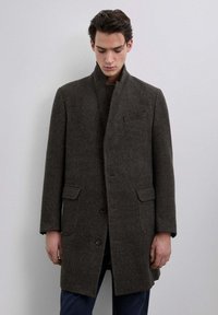 Abrigo de lana en gris oscuro con patrón de espiga, con un cuello alto, dos bolsillos frontales y un cierre de un solo botón.