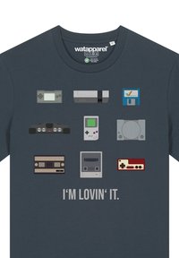 Navy t-shirt featuring pixel art of retro gaming consoles and controllers in various colors, with the text "I'M LOVIN' IT" below.