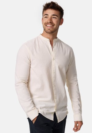 Langermet skjorte med knapper i kremfarge med vertikale lyse striper, krageløst design, teksturert stoff og avslappet passform.