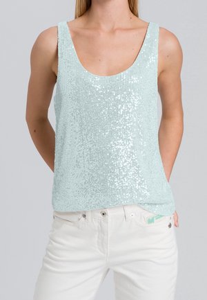 Débardeur en sequins bleu clair avec un col rond et sans manches. Présente une coupe décontractée et une texture lisse. Associé à un jean blanc.