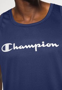 Navy blue athletic tank top with mesh texture, featuring large white "Champion" logo across the chest and a classic round neckline.